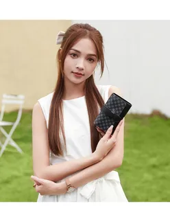 Close-up of a women's checkerboard pattern wallet held by a model in natural light