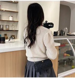 Model wearing a black quilted cylinder crossbody bag with golden chain and floral detail