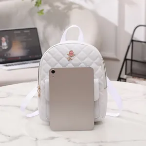 Mini zaino bianco trapuntato con logo rosa accanto a un tablet per confronto taglie