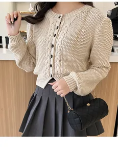 Close-up of black quilted cylinder chain bag with floral gold clasp on knit cardigan