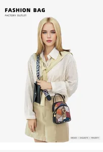 Detail of color-block PU leather bag with wide printed strap and a small cat charm