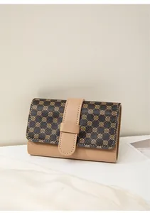 Macro detail of retro patterned women's purse with gold clover print and beige strap