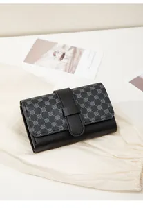 Detail of black faux leather mini wallet with gray geometric pattern and tab closure