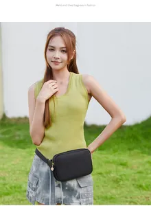 Modische schwarze Nylon-Gürteltasche mit goldenem Reißverschluss an einem Modell vor grünem Rasen