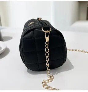 Detail of black quilted cylindrical bag showing gold chain strap and stitching textures