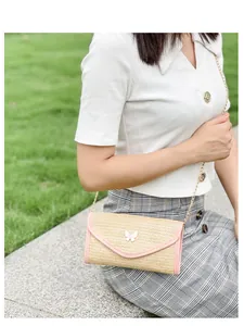 Detail of woven straw crossbody bag with pink leather trim and white butterfly ornament