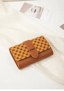 Close-up of brown folding wallet with black geometric patterns and tuck buckle closure