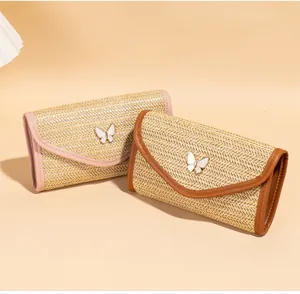 Detail view of woven shoulder bag with butterfly charm and colorful PU leather edging