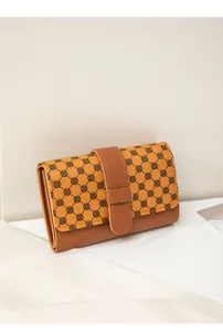 Detail shot of vintage patterned wallet flap with brown faux leather contrast and strap