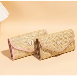 Detail of woven straw envelope bags with butterfly buckles and leather trim in soft light