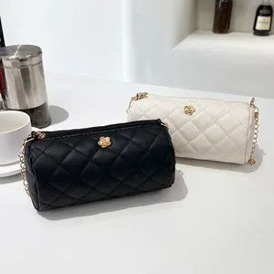Quilted cylinder crossbody bag with golden flower detail and metal chain straps