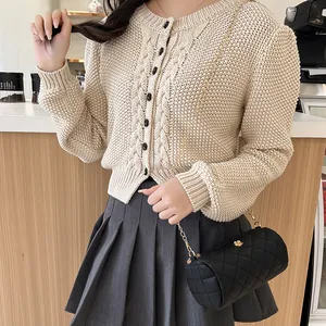 Woman wearing a beige quilted cylinder crossbody bag with gold chain and floral detail