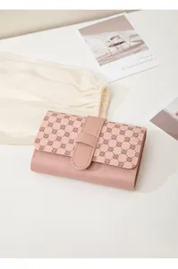 Detail of a pink tri-fold wallet featuring a clover pattern and buckle closure
