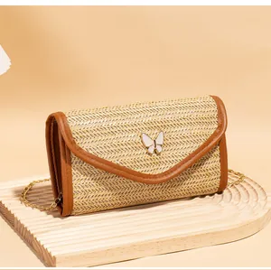 Detail of woven straw shoulder bag with brown leather trim and white butterfly clasp