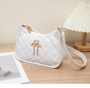 Nahaufnahme der weißen Stepptasche mit goldenem Schwanen-Herzanhänger und Fransen