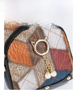Detailed macro view of quilted faux leather patchwork and golden cat charm on bag