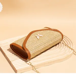 Close-up of woven straw shoulder bag with butterfly detail and gold chain strap