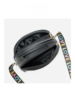Detail view of black crossbody bag with three zipper compartments and rainbow LOVE strap
