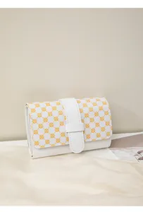 Detail view of mini wallet showing yellow clover patterns and side gusset on silk