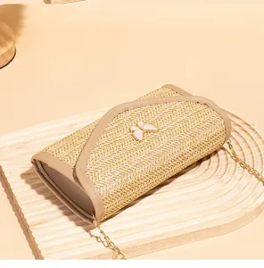 Close-up of woven small square bag featuring a white butterfly ornament and chain strap