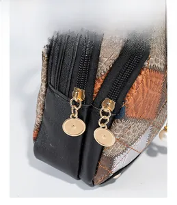 Detail view of double gold zippers and quilted stitching on a multi-layer shoulder bag