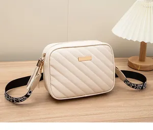 Dettaglio borsa a tracolla beige trapuntata con nappa e ampia tracolla con scritte