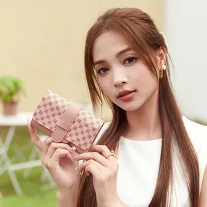 Elegant pink geometric patterned leather mini wallet held by a model in a garden