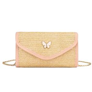 Beige straw woven crossbody bag with pink trim, butterfly clasp and gold chain strap