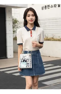 Close-up of transparent PVC crossbody bag with white daisy print and golden chain strap
