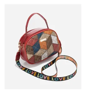 Detail of red crossbody bag with patchwork faux leather and colorful LOVE strap