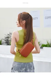 Makrodetail der lässigen orangefarbenen Brusttasche mit verstellbarem Gurt und Metallzipper