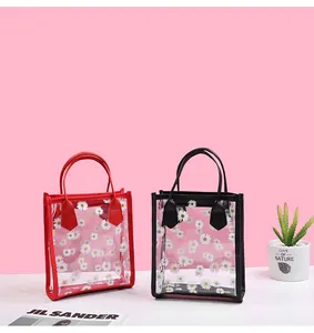 Close-up of transparent PVC crossbody bags with daisy prints and colorful chain handles