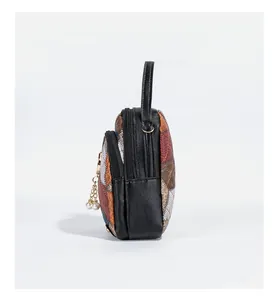Detail view of the multi-layer zipper and pearl charm on this patchwork crossbody bag