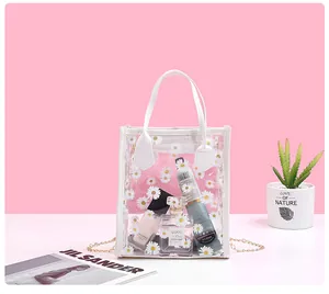 Detail of transparent PVC crossbody bag with white daisy prints and gold chain strap