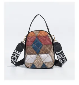 Close-up of color-block patchwork bag with crocodile texture and wide lettered strap