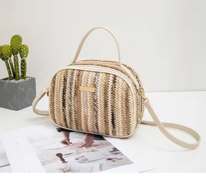 Detail der gewebten Handtasche mit goldener Metallplatte und beigen Ledergriffen