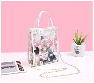 Detail of transparent PVC crossbody bag with white daisy prints and gold metal chain strap