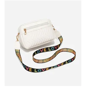 Detail van witte gewatteerde crossbodytas met kleurrijke LOVE-band en gouden hardware