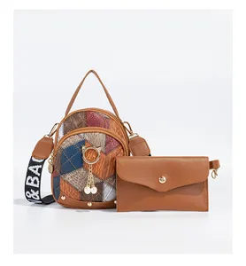 Detail view of the patchwork shoulder bag featuring cat charm and pearl accents with envelope pouch