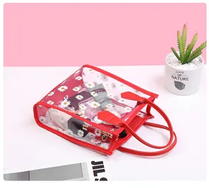 Detail of transparent PVC daisy handbag with bright red trim and heart zipper pull