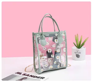 Detail view of transparent PVC crossbody bag with white daisy prints and green leather handle