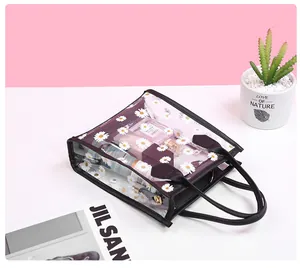 Detailed view of clear PVC daisy print handbag featuring black leather trim and handles