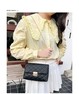 Outdoor model display of a black quilted chain crossbody bag with gold square lock closure