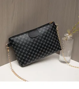 Detail of black crossbody bag with textured geometric pattern and gold chain strap