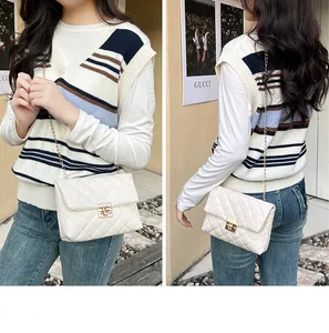 Detailed view of white quilted crossbody bag with gold chain strap and turn-lock closure