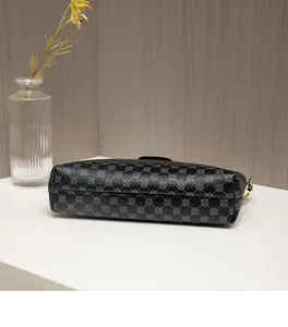 Detail view of the black crossbody bag bottom with grey clover pattern and gold metal hooks