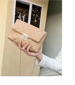 Detailed close-up of quilted beige leather crossbody bag with golden rectangular push lock