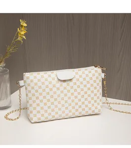 Close-up of white crossbody bag featuring yellow geometric patterns and gold chain