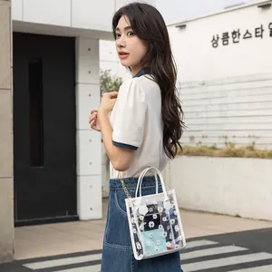 Transparent daisy print tote bag with gold chain strap shown on model in street setting