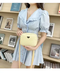 Detail of woven texture beige camera bag with triangle logo on blue dress background